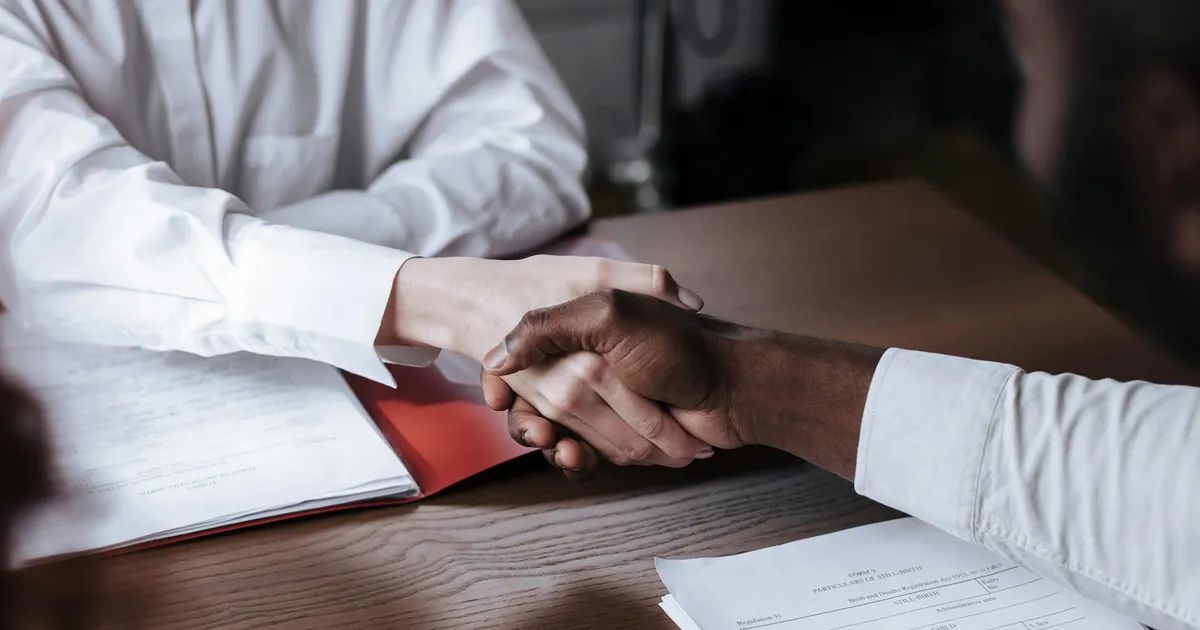Poignée de main professionnelle au-dessus de documents contractuels symbolisant la signature avec une agence web