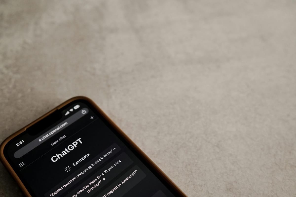 smartphone posé sur un bureau affichant l'interface ChatGPT d'OpenAI avec exemples de questions à l'écran