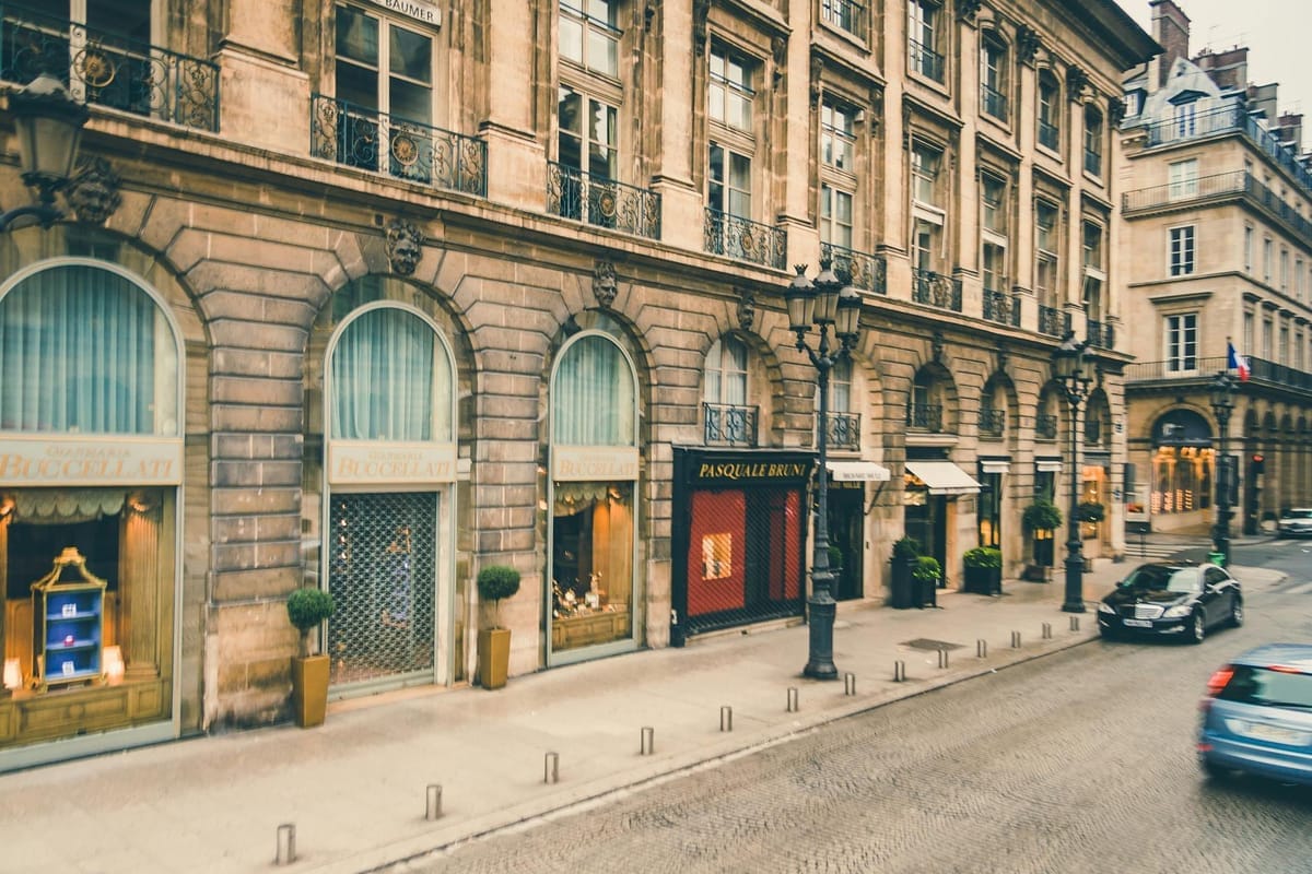 rue commerçante parisienne avec plusieurs vitrines de boutiques sous lampadaires classiques et façades haussmanniennes