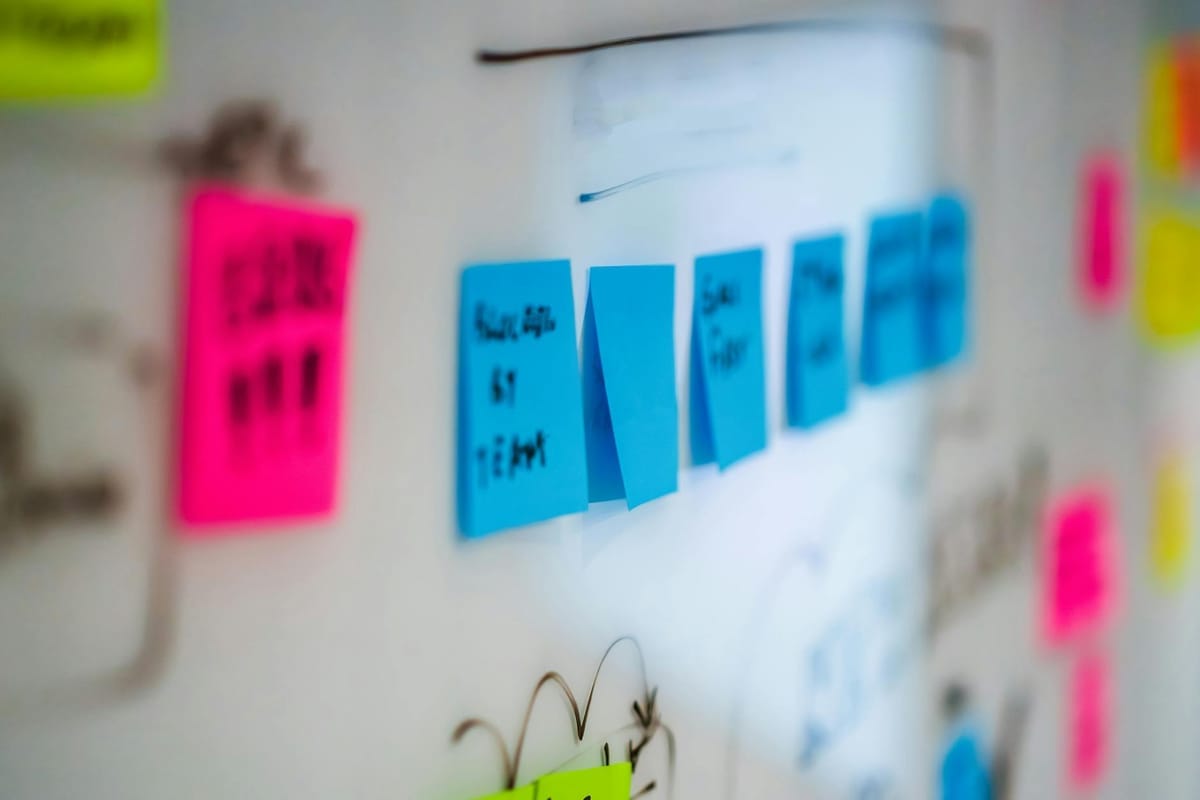 tableau blanc couvert de post-it roses bleus et jaunes structurant une stratégie marketing dans un bureau lumineux